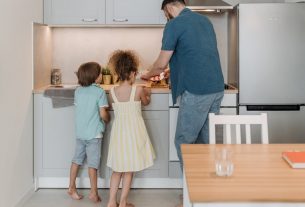 Father and children cooking together in a modern kitchen, enjoying family time.